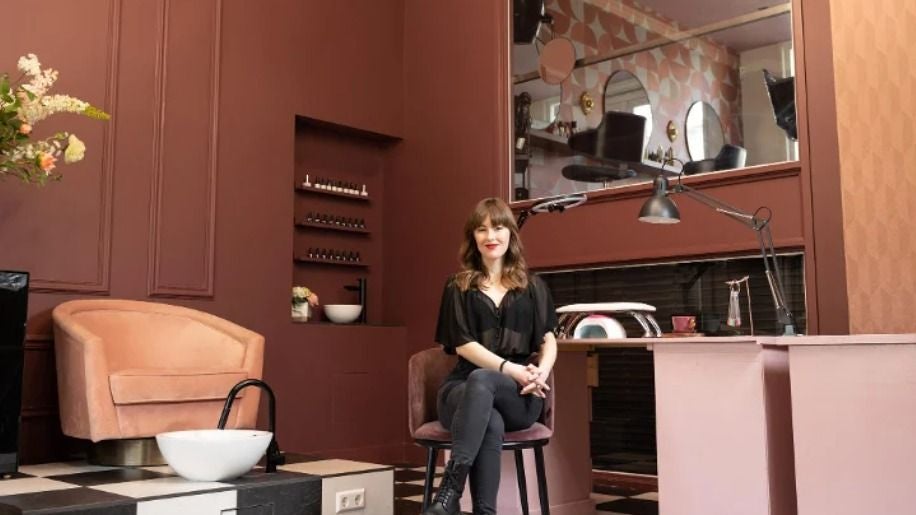 Een vrouw zit aan de manicuretafel in de salon