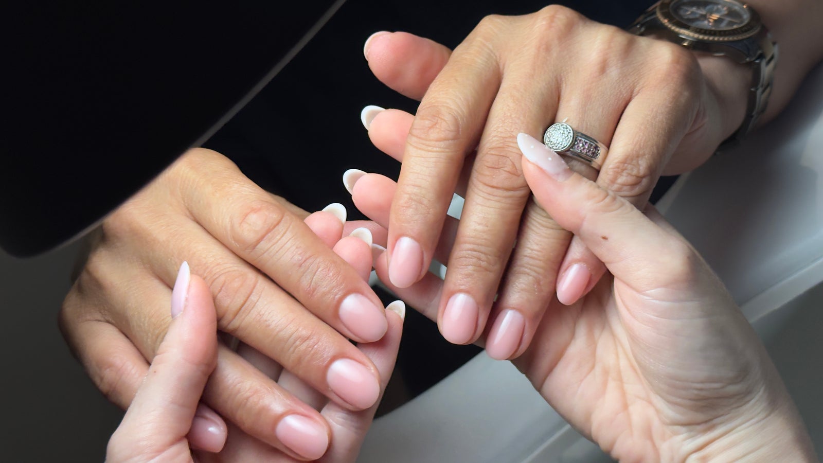 Handen met zachtroze nagels tijdens een manicure